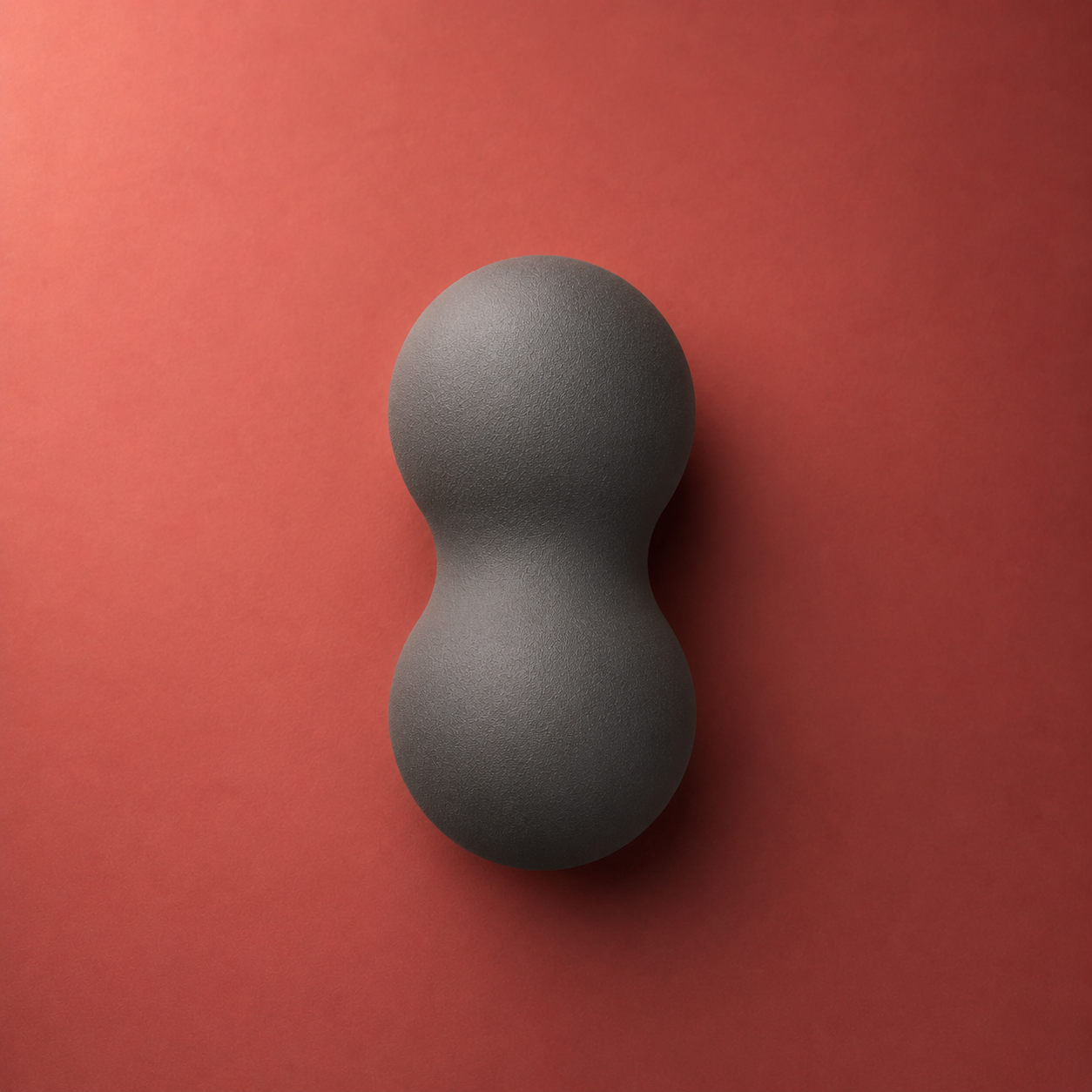 Peanut massage ball top-down figure-8 view on warm crimson studio backdrop
