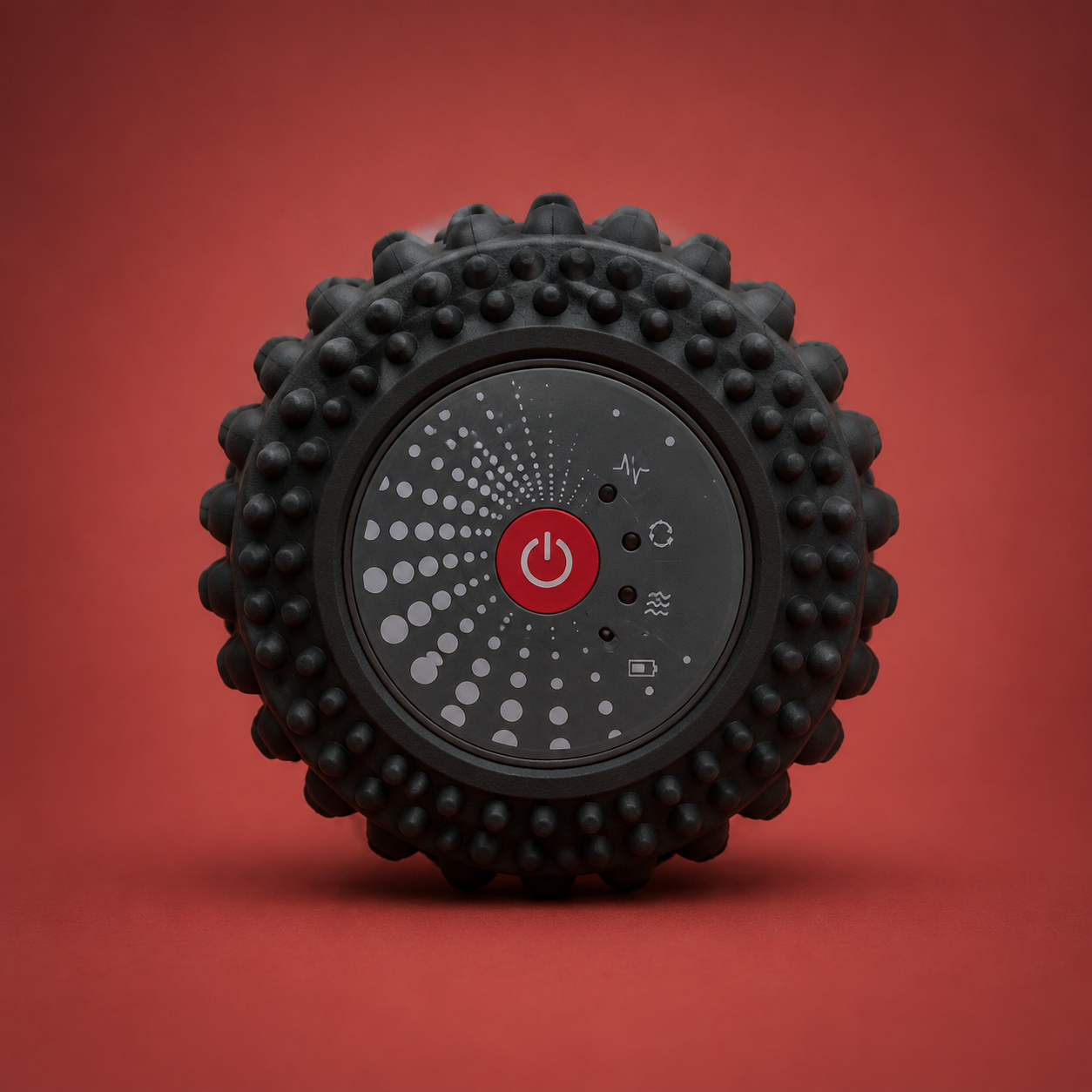 Vibrating foam roller end-cap control face — red power button and spiked rim on warm crimson backdrop